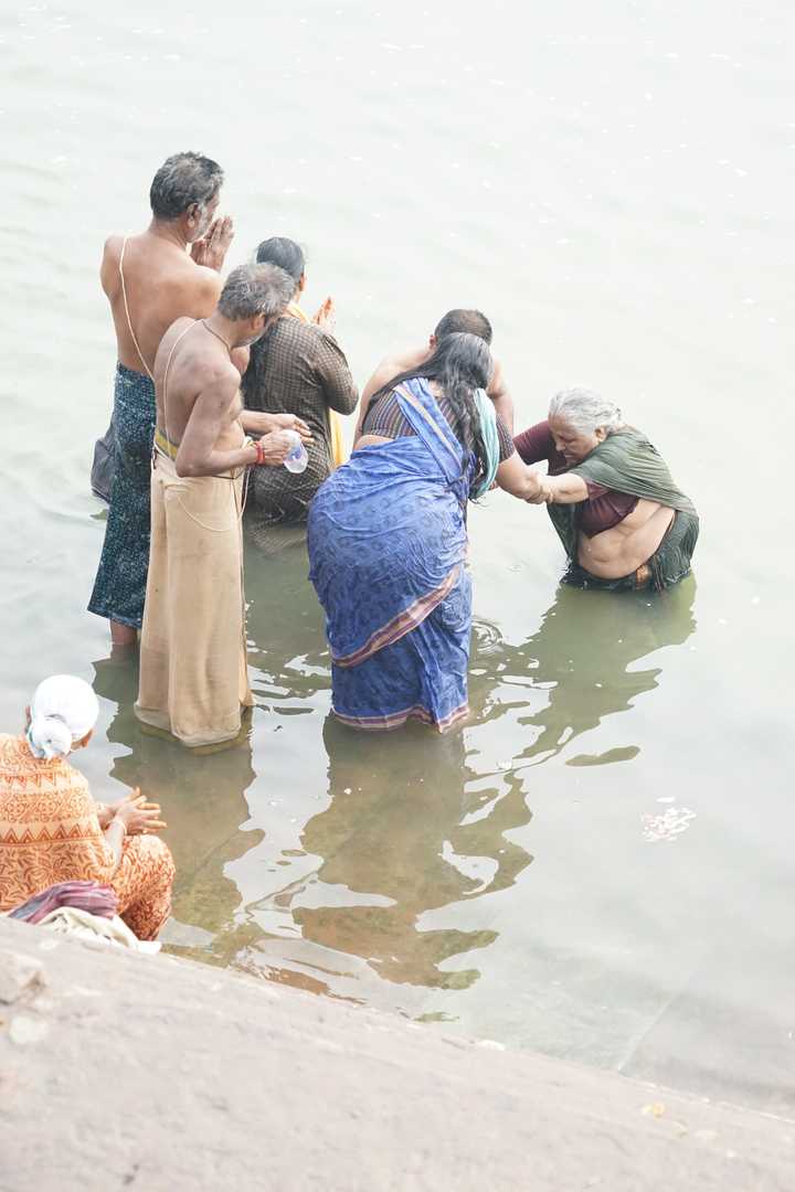 着印度传统民族服装的男男女女背朝岸上,将整个下半身浸泡在恒河水中