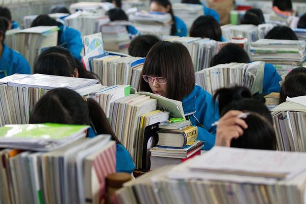 河南驻马店,教室内,正在学习的学生,课桌上厚厚堆起的书本作业挡得