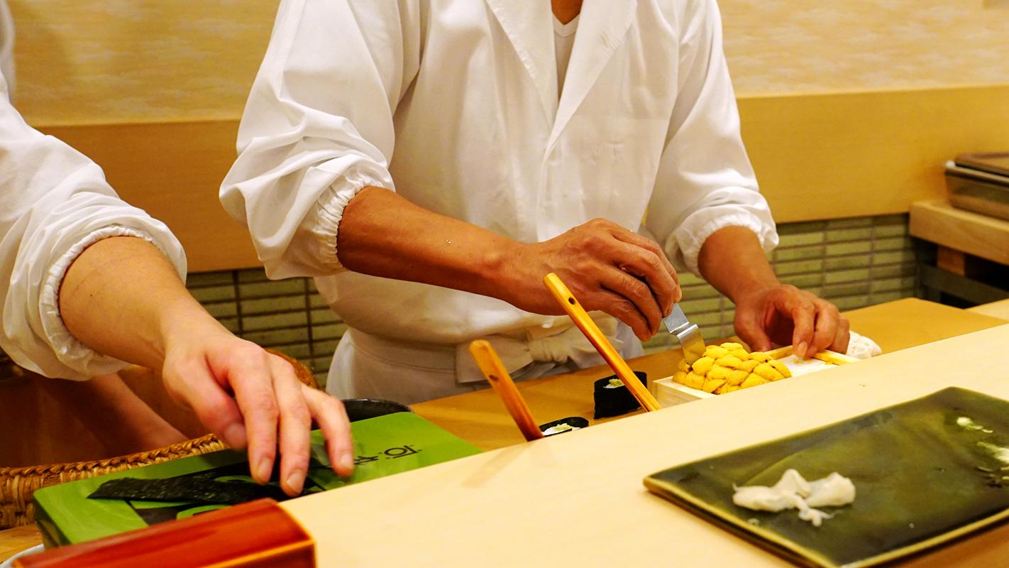 隆士先按照人数份捏出饭团,然后副厨挨个卷上海苔,再由隆士往上面盖