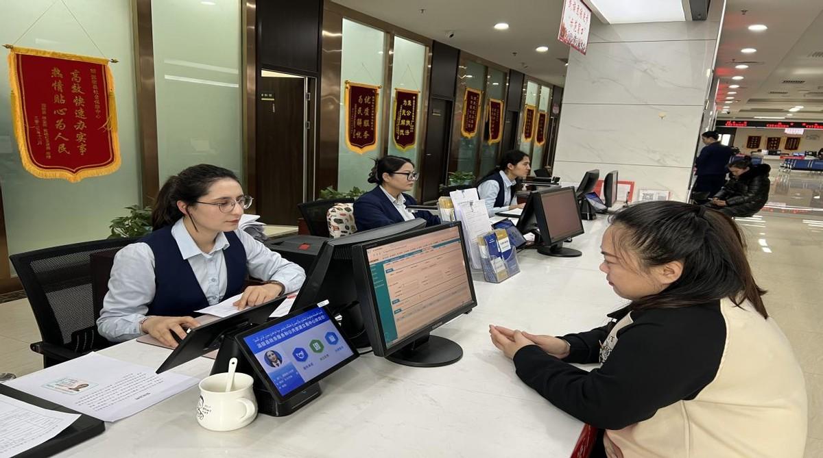 图为:温宿县社保中心综柜窗口工作人员为群众办理社保业务(江凯摄)图
