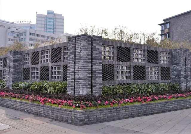 在青羊区省医院地铁站一排镂空的围墙外,青翠的绿竹和嫣红的鲜花分外