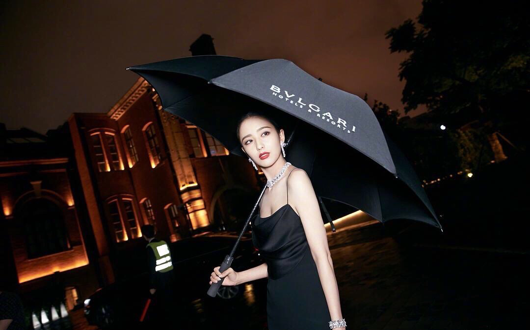 酒红色吊带亮片裙与商务伞的完美结合之下,倪妮像是上世纪的港片女郎